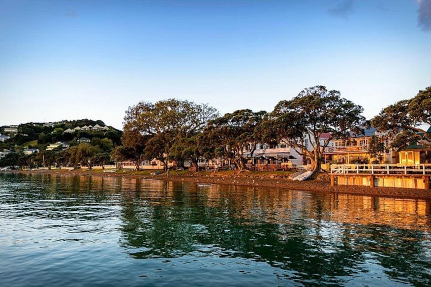 A calm lake with reflections of trees and buildings, surrounded by a small dock and a hill with houses in the background. 3
