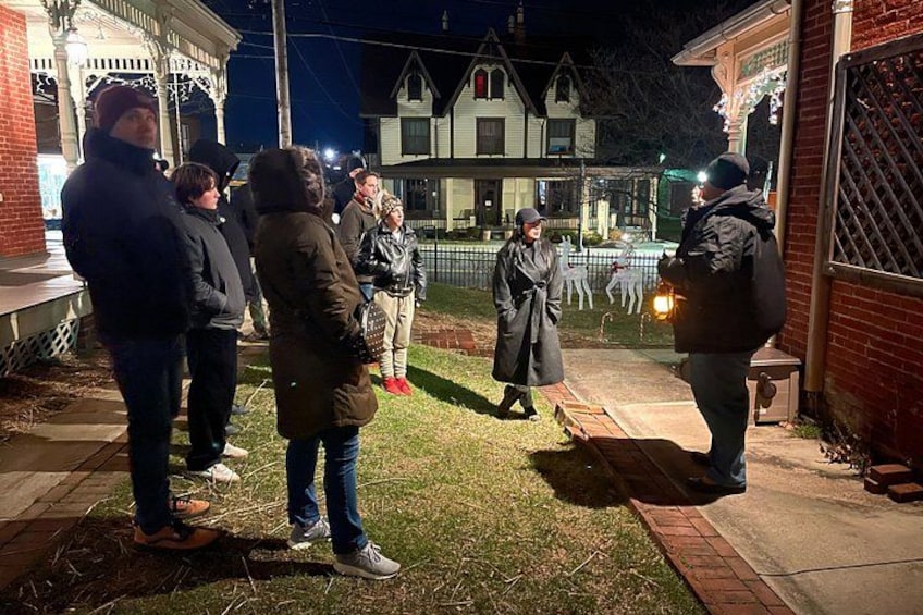 Een groep mensen staat voor een huis in de nacht. 4