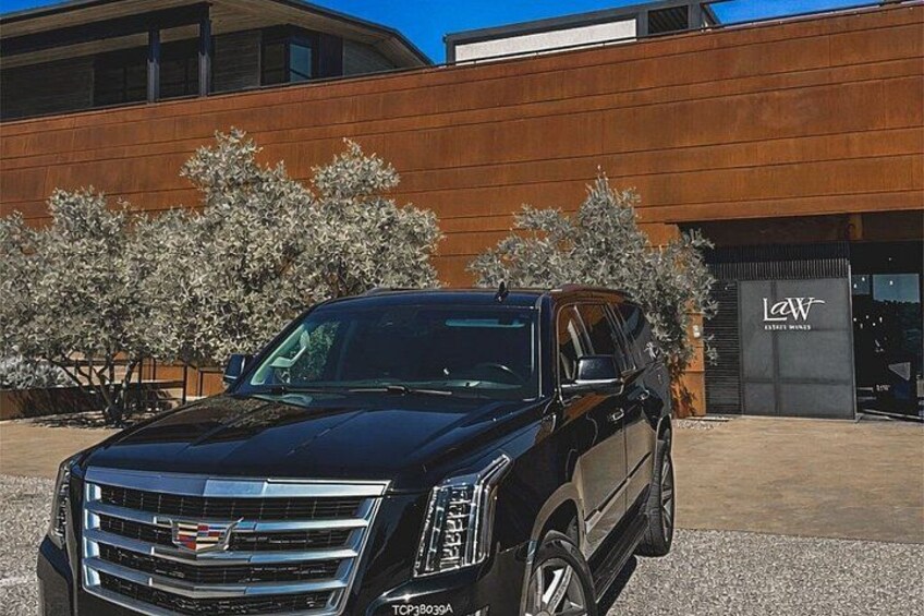 A black Cadillac SUV parked in front of a building with a sign that reads 'LAW.' 3