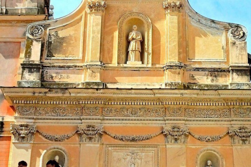 A building facade with ornate carvings, a central statue, and an arched window. 4