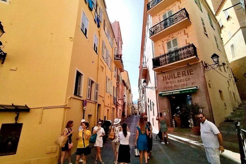A narrow street with yellow buildings, a shop named 'HUIERIE,' and people walking. 2
