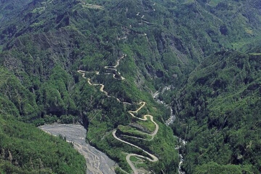 Une route de montagne sinueuse qui traverse une forêt dense. 2