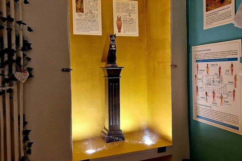 Una vitrina con una estatua, carteles informativos y un diagrama en la pared. 3