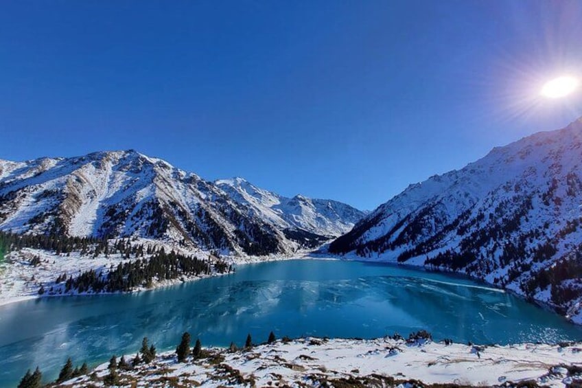 A snow-covered mountain range, a turquoise lake, and a clear blue sky. 2