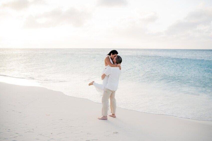 A couple embracing on a beach with the ocean in the background. 3