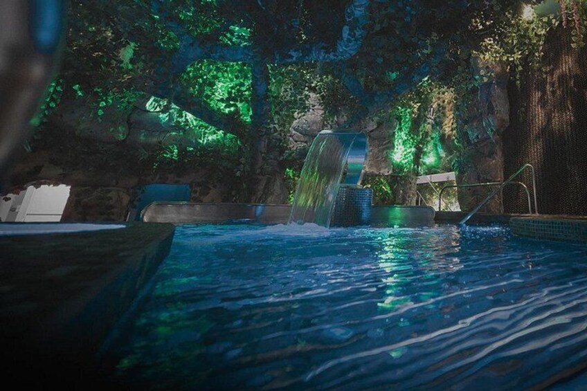 Una piscina con cascada, rodeada de formaciones rocosas y vegetación. 2