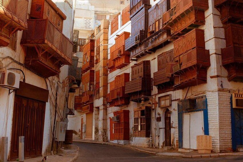 A narrow street flanked by multi-story buildings with wooden balconies and traditional doors. 1