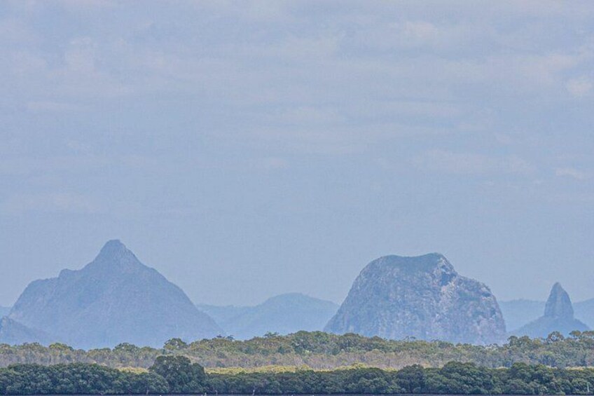 A mountainous landscape with prominent peaks and a dense forest in the foreground. 4