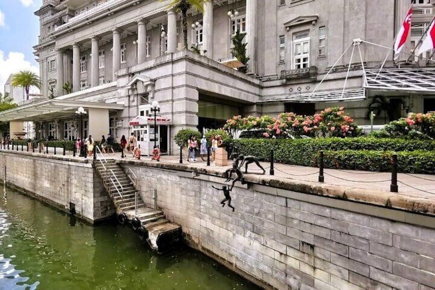 Un paseo marítimo con un puente de piedra, un edificio grande con columnas y gente caminando. 1