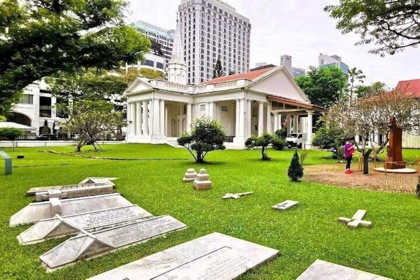 Un cementerio con lápidas, un edificio blanco con columnas y un paisaje urbano al fondo. 2