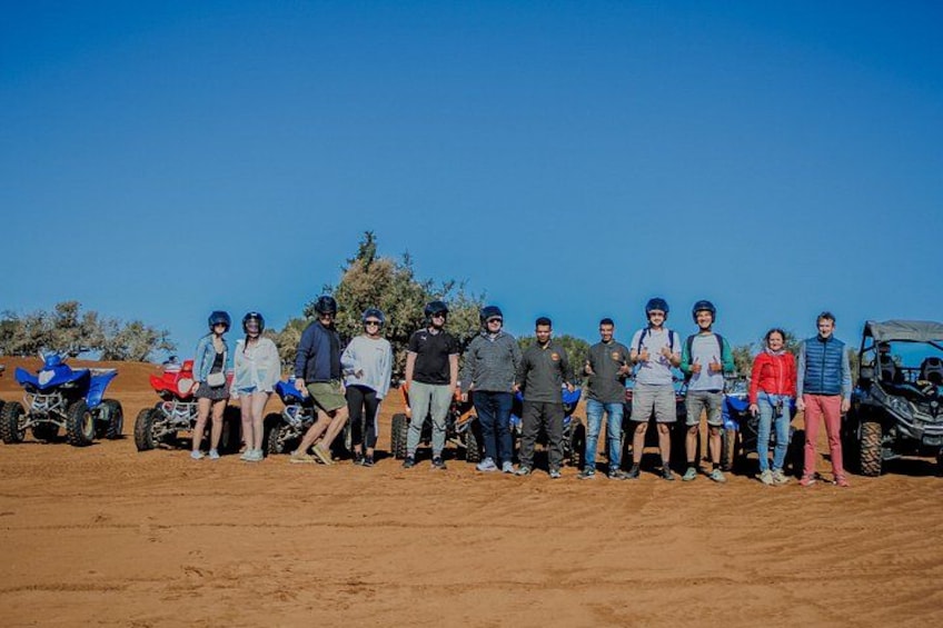 A group of people standing in a desert with off-road vehicles. 5