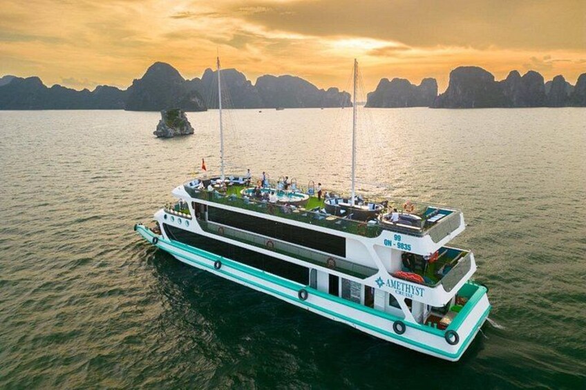 A large boat with multiple decks, a flag, and the name 'AMETHYST' on its side, floating on water with a mountainous coastline in the background. 4