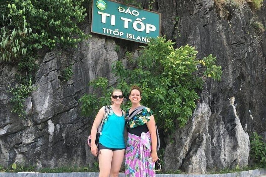Two people standing in front of a rocky cliff with a sign that reads 'ĐÀO TI TÔP TÌTÔP ISLANDS'. 5