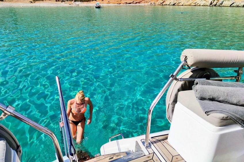 Une personne en bikini qui descend d’un bateau et pose le pied sur une étendue d’eau d’un bleu limpide. 4