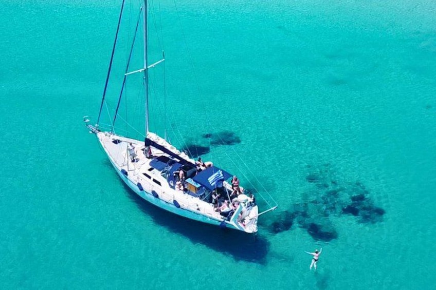 Un velero con pasajeros y una persona nadando cerca. 1
