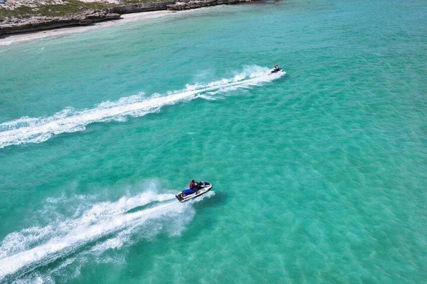 Two jet skis on turquoise water with a sandy beach in the background. 2