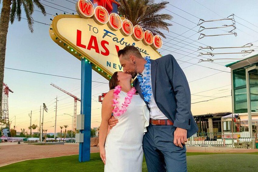 A couple kissing in front of a 'Welcome to Fabulous Las Vegas' sign. 1