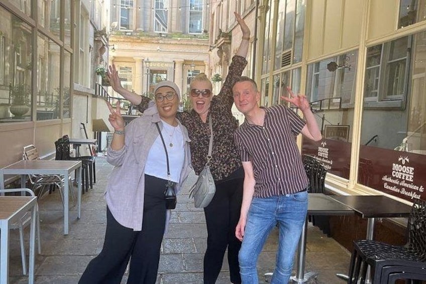 Three people posing in a café with large windows and outdoor seating. 5