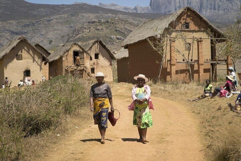 A dirt road with traditional houses and people walking. 1