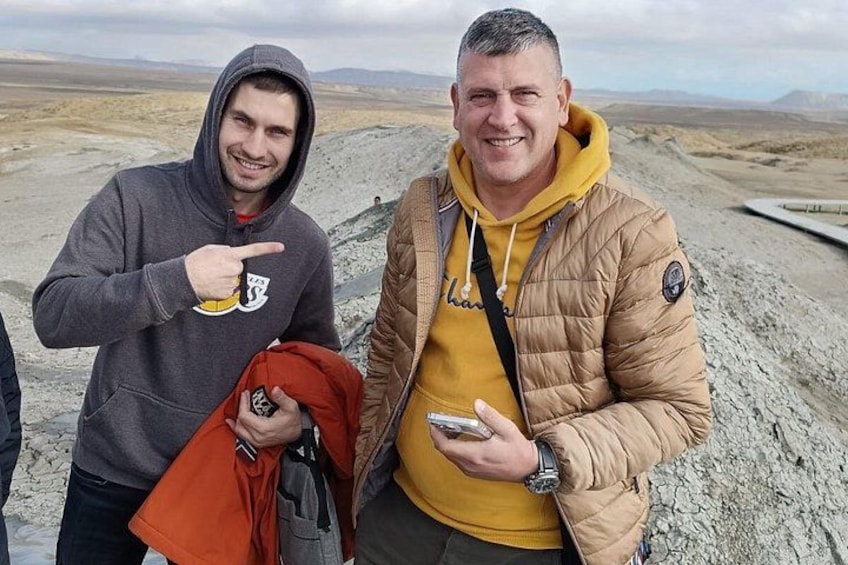 Dos personas en un entorno rocoso al aire libre, una sosteniendo un teléfono y la otra señalando. 2