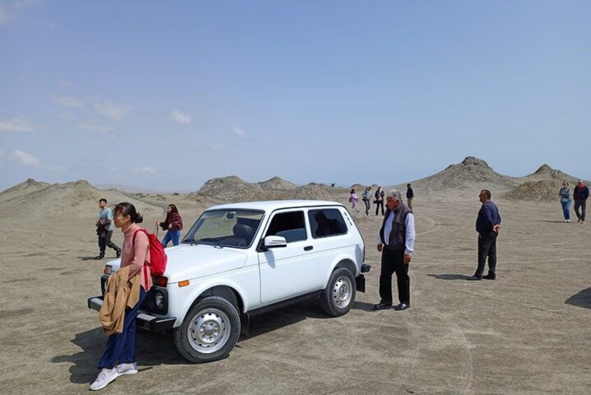Een witte SUV staat op zand, met mensen eromheen. 3