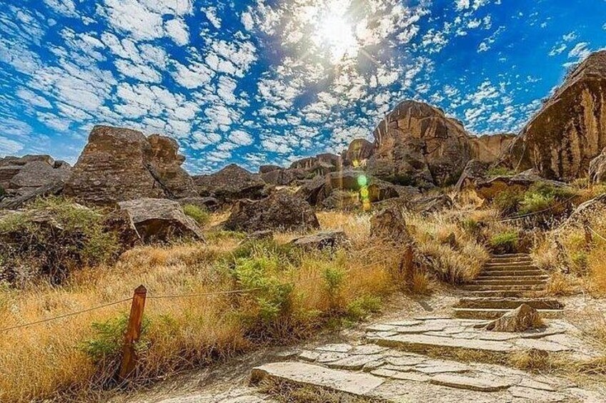 Un paisaje rocoso con una escalera de piedra que sube hacia una gran formación rocosa. 5