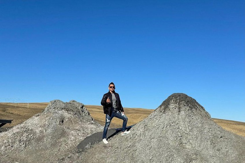 Una persona está de pie entre dos montones de grava en un paisaje llano bajo un cielo azul despejado. 3