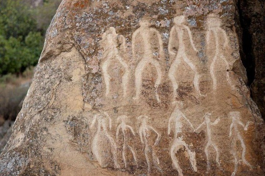 Una roca con figuras humanas antiguas talladas. 1