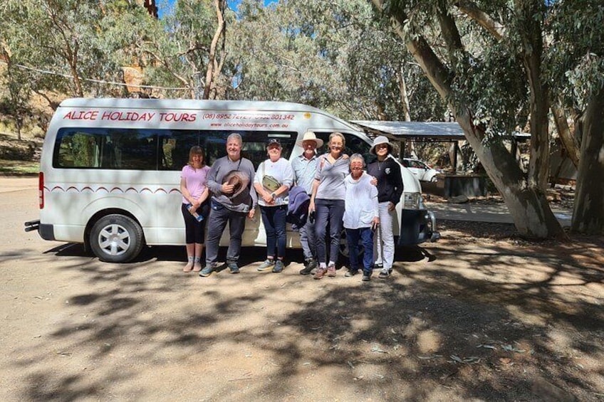 A group of people standing in front of a tour bus with the text 'ALICE HOLIDAY TOURS' on its side. 1
