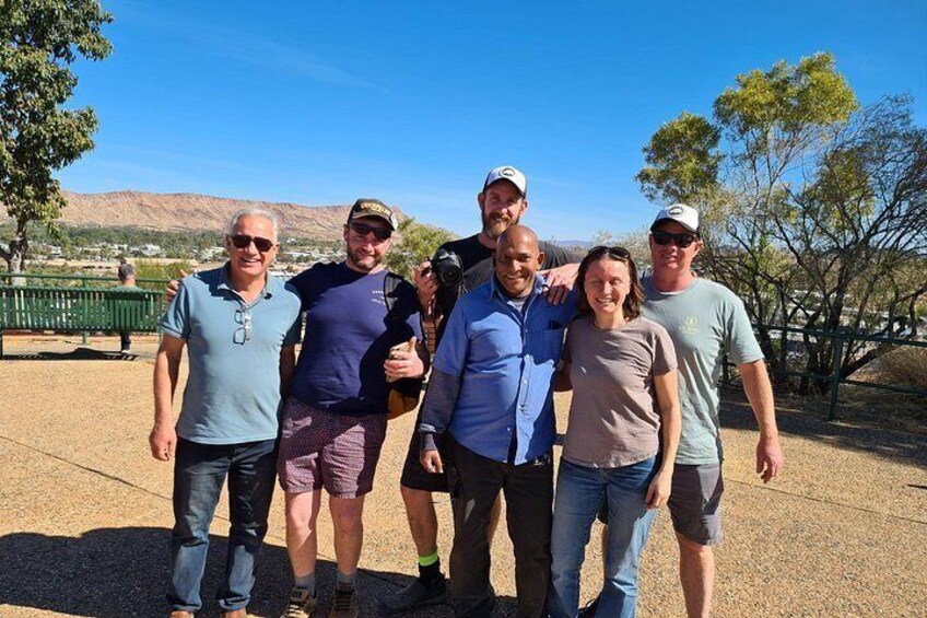 A group of people standing outdoors with a clear sky and a hilly landscape in the background. 2
