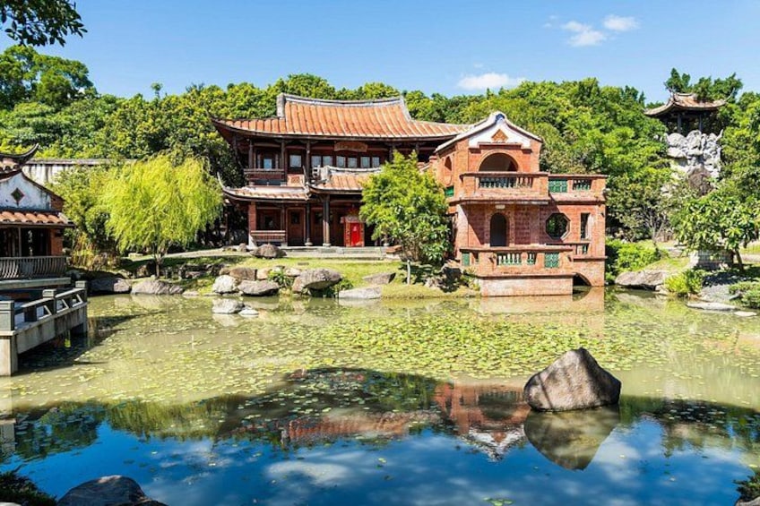 A traditional Chinese garden with a pond, a red-roofed building, and a stone bridge. 2