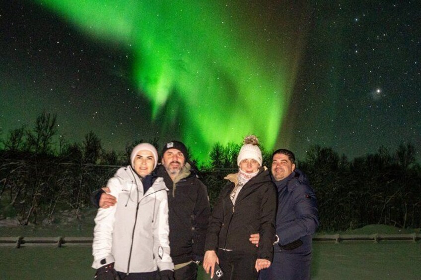 Four people posing under the Northern Lights. 2