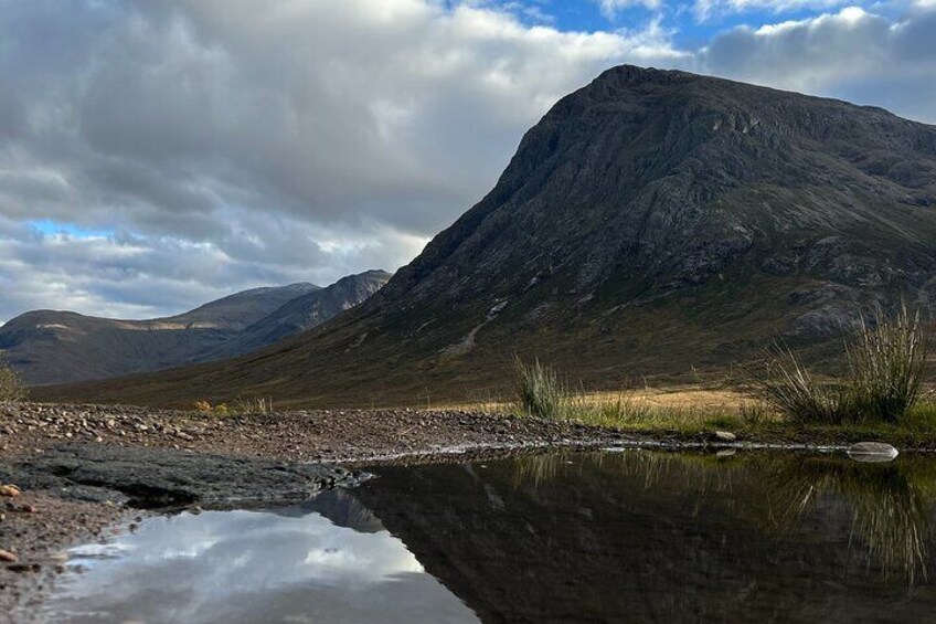 Un paysage de montagne avec une étendue d’eau qui reflète l’environnement et un ciel dégagé. 2