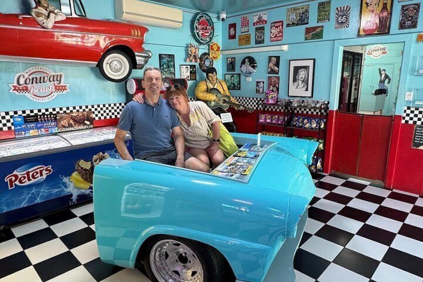 A vintage car ride in a retro-themed room with a checkered floor, a red car on the wall, and various memorabilia. 4