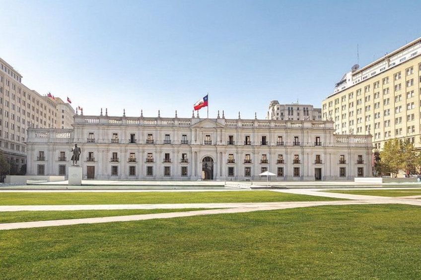 A large, historic building with a flag, surrounded by a well-maintained lawn and other buildings. 1