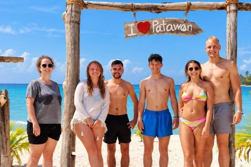 A group of people standing under a wooden structure with a sign that says 'I love Patawan.' 3