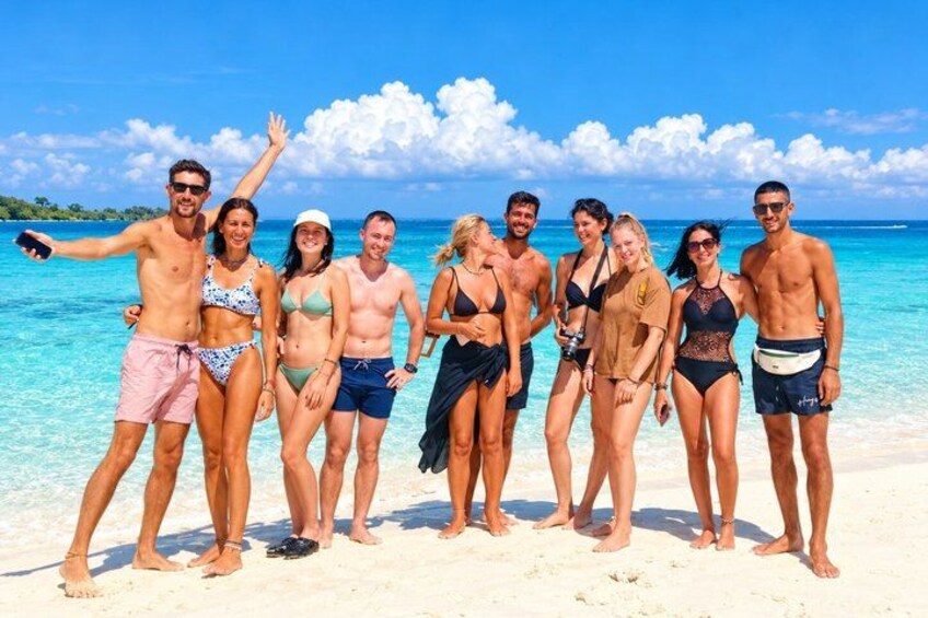 A group of people on a beach with clear blue water and a sandy shore. 5