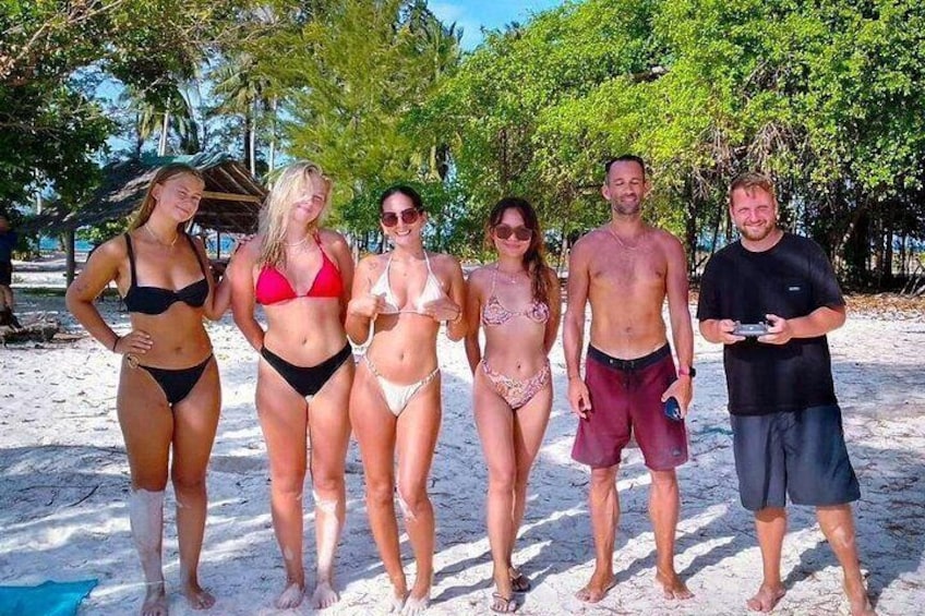 A group of people on a sandy beach with palm trees in the background. 4