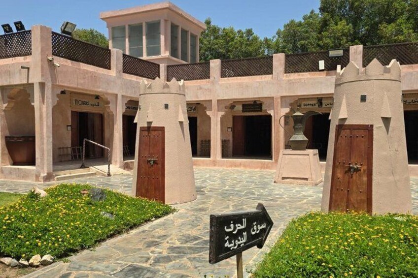A courtyard with a central tower, a sign indicating a direction, and a building with multiple doors. 3