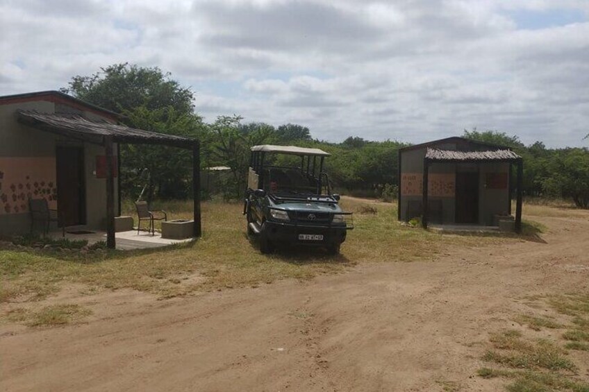 A dirt road with a vehicle parked between two small buildings. 5