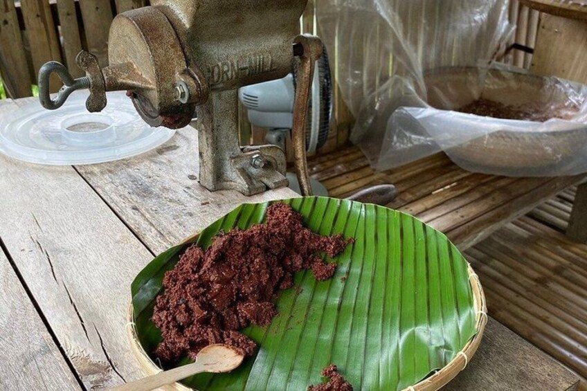 Un ensemble d’ustensiles traditionnels pour la préparation des aliments, comprenant un moulin manuel, une feuille de bananier et un sac en plastique. 2