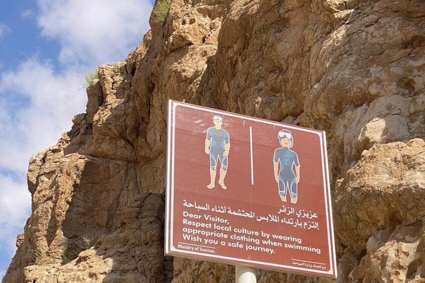 Une falaise rocheuse sur laquelle est affiché un panneau invitant les visiteurs à porter des vêtements appropriés et à se baigner en toute sécurité. 1