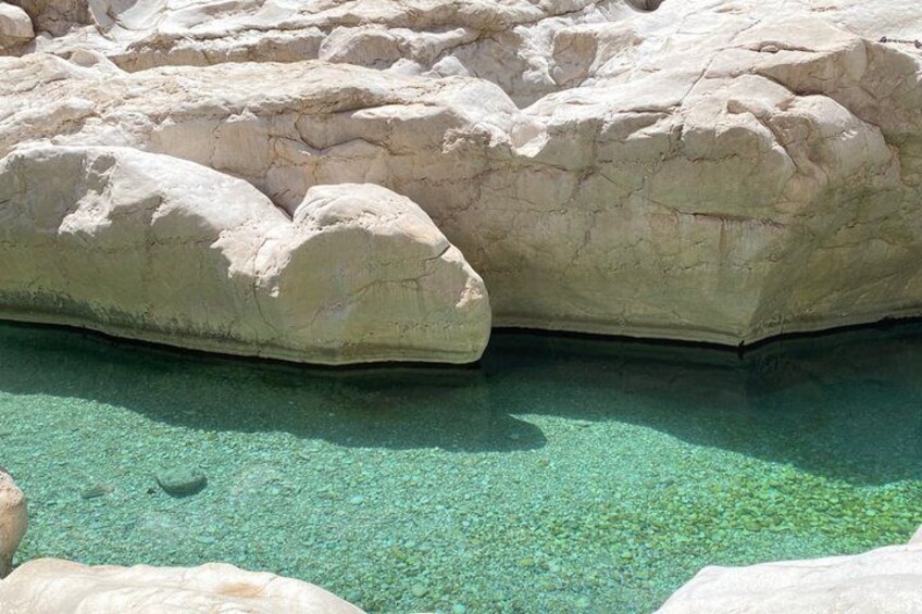 Une grande formation rocheuse avec de l’eau claire à ses pieds. 3