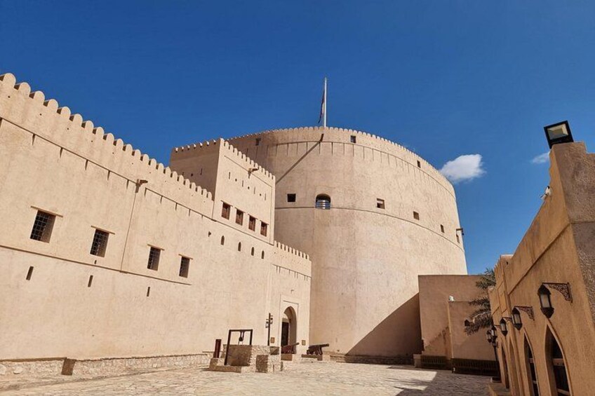 A large, historic building with a round tower, arched doorways, and a fortified wall. 2