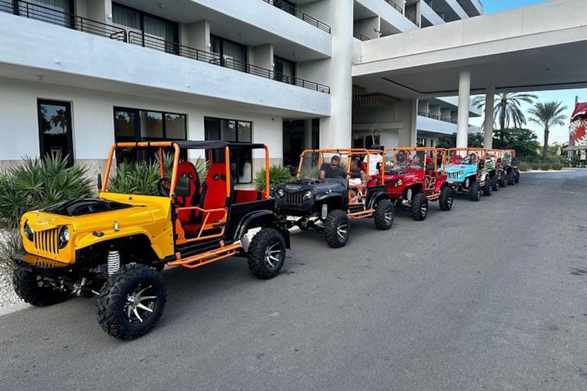 A row of colorful jeeps parked in front of a building. 1