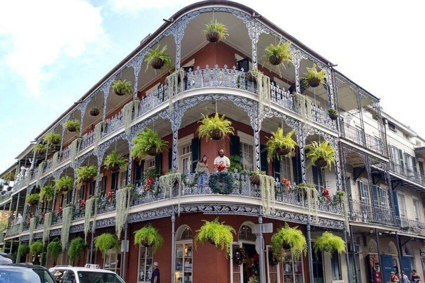 Un edificio histórico con balcones ornamentados, ventanas amplias y plantas colgantes. 2