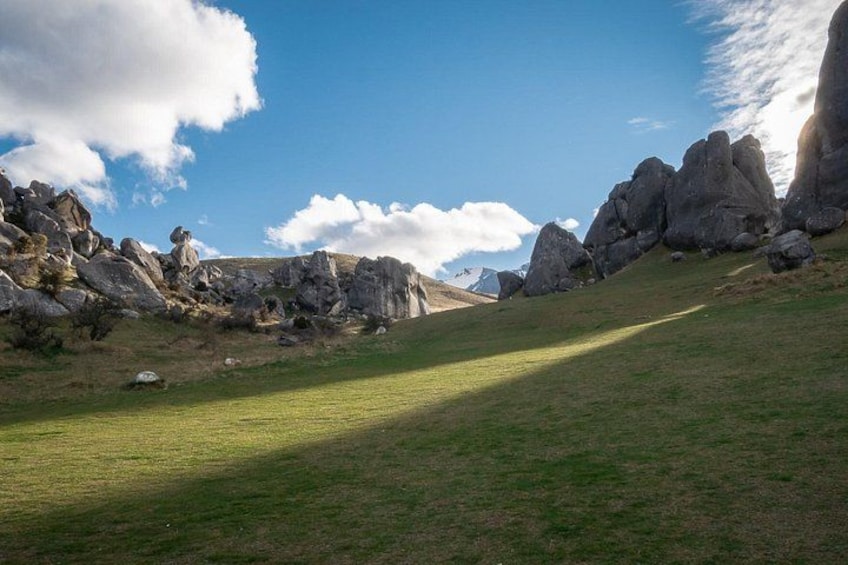 A grassy hillside with large boulders and a clear blue sky. 2