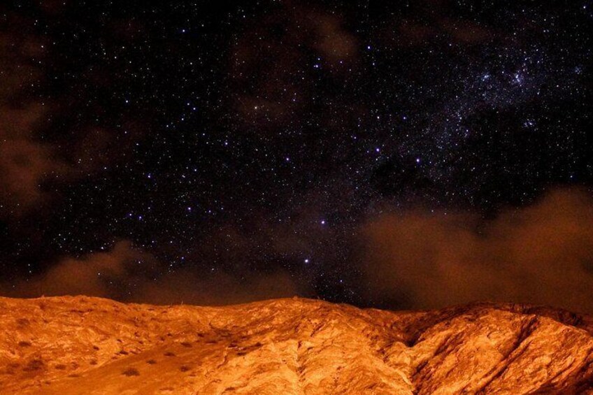 A night sky filled with stars and the Milky Way over a rocky landscape. 4