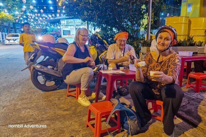 Three people sitting at a table outdoors at night. 4