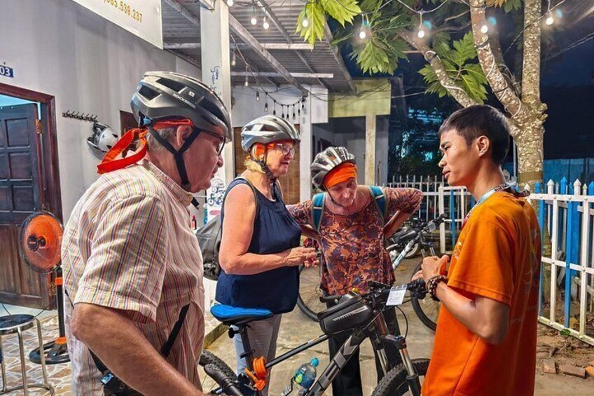 A group of people with bicycles, a tree, and a building in the background. 5